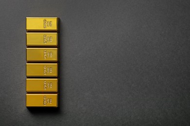 Many shiny gold bars on black background, flat lay. Space for text