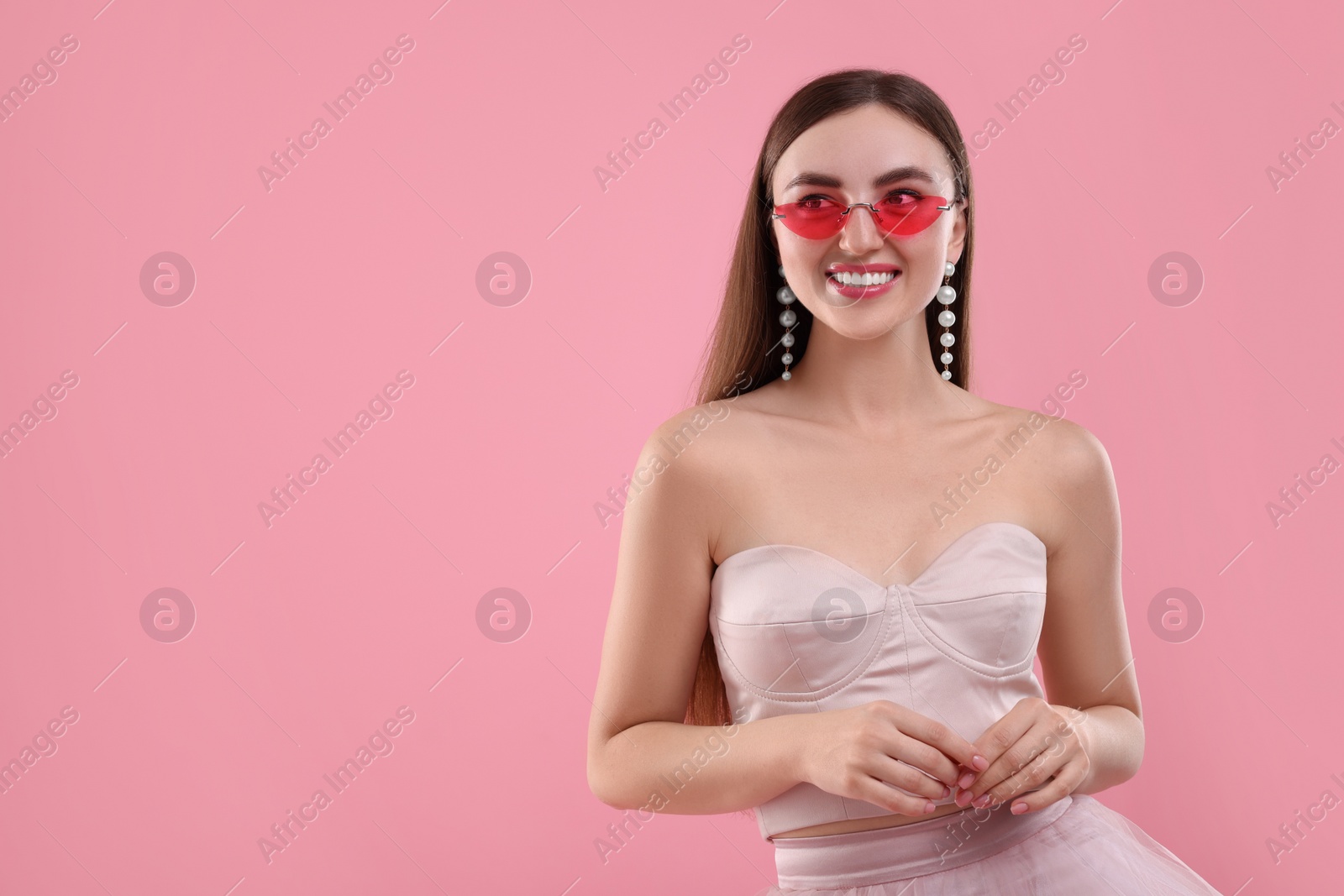 Photo of Pink look. Beautiful woman in clothes and bright sunglasses on color background, space for text