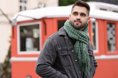 Handsome man in warm scarf outdoors. Space for text