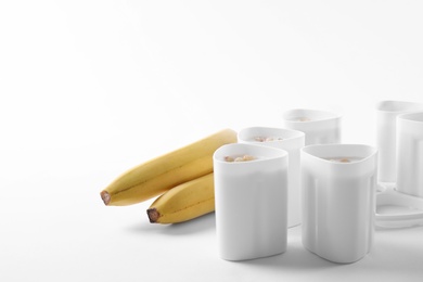 Photo of Cups of yogurt with bananas on white background. Multi cooker recipe