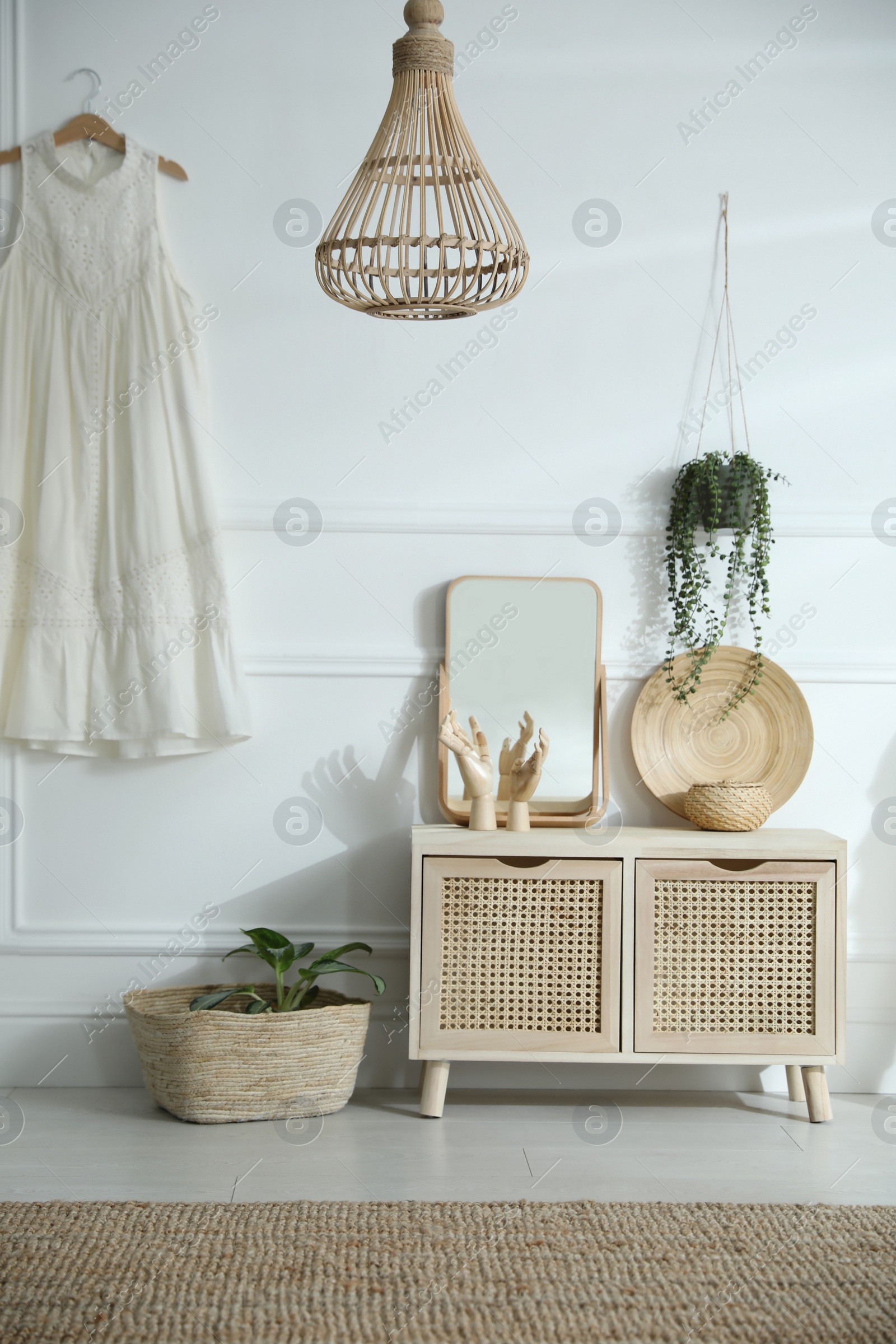 Photo of Wooden commode near white wall in room. Interior design