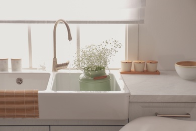 Photo of Bouquet of gypsophila flowers in sink. Kitchen interior design