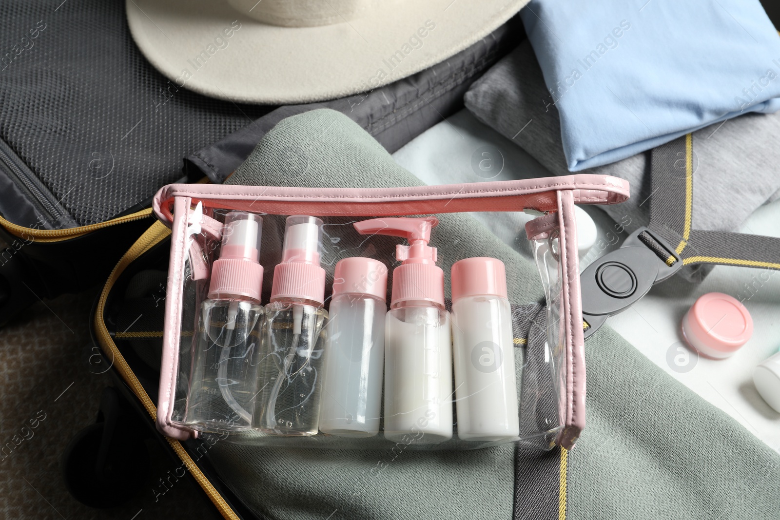 Photo of Plastic bag of cosmetic travel kit in suitcase, top view