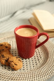 Cup of aromatic coffee, cookies and book on soft blanket