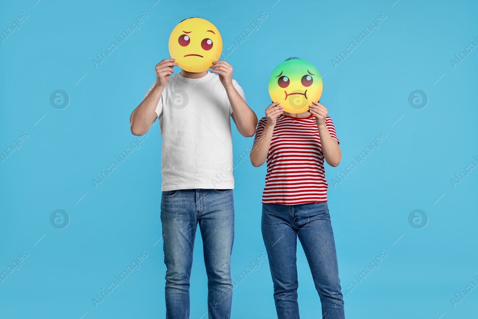 Photo of People covering faces with emoticons on light blue background