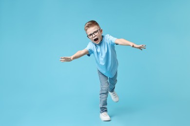 Happy little boy dancing on light blue background