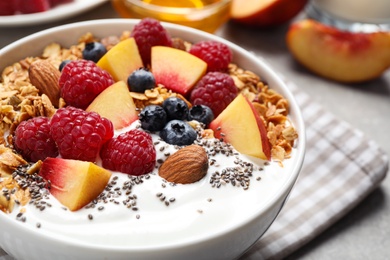 Photo of Tasty homemade granola with yogurt served on grey table, closeup. Healthy breakfast