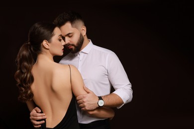Photo of Handsome bearded man with sexy lady on dark background. Space for text