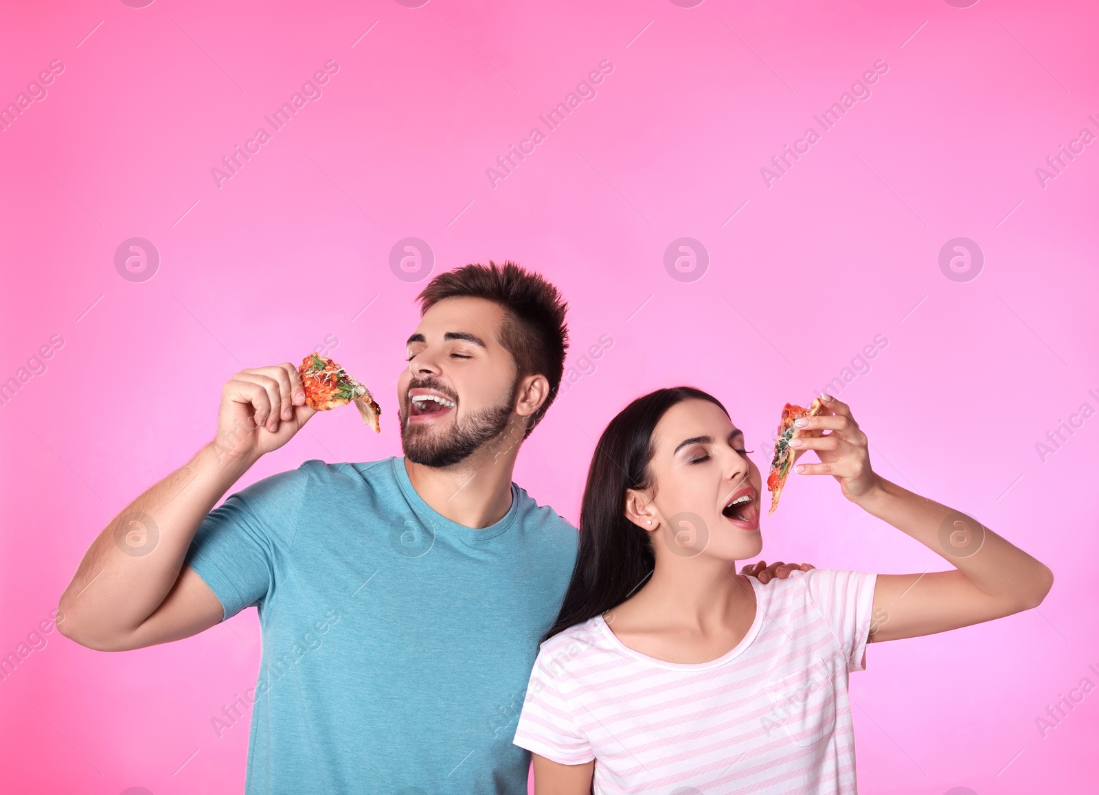 Photo of Happy couple with pizza on pink background