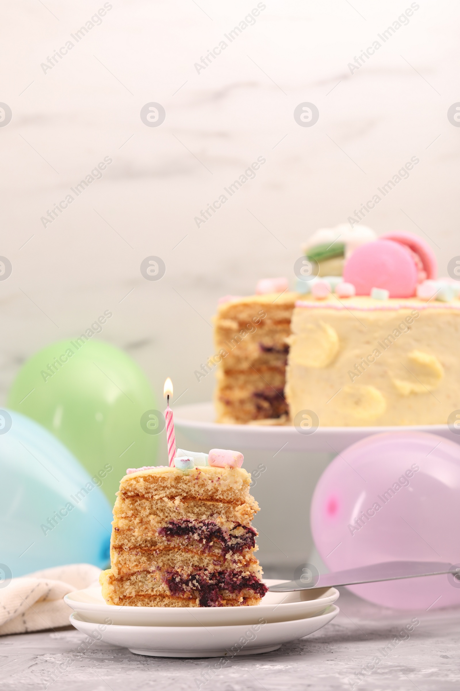 Photo of Piece of delicious cake with burning candle on light grey table, space for text