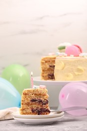 Photo of Piece of delicious cake with burning candle on light grey table, space for text