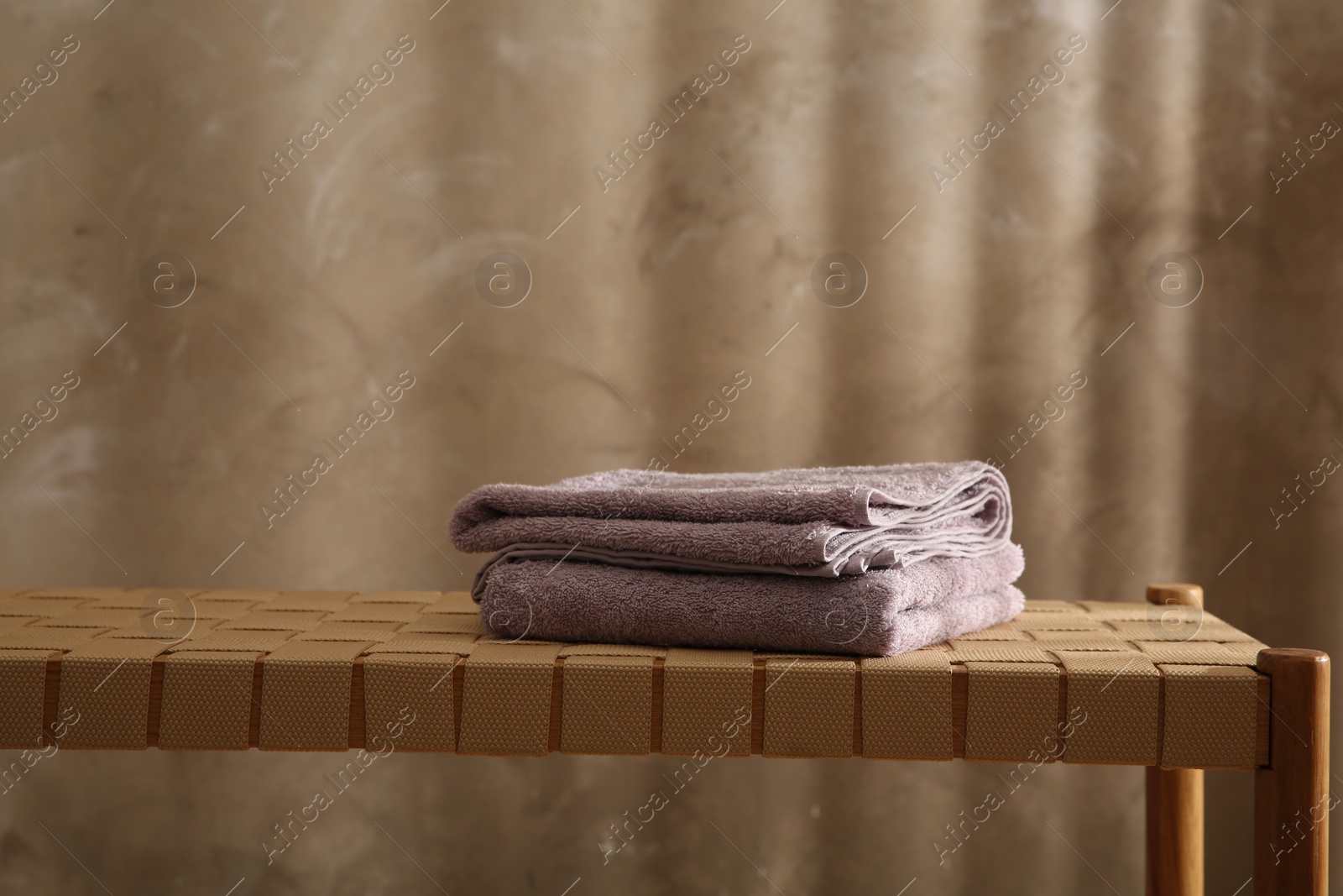 Photo of Soft terry towels on wicker bench indoors