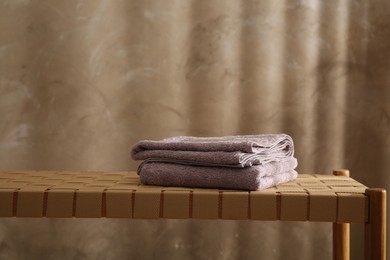 Photo of Soft terry towels on wicker bench indoors