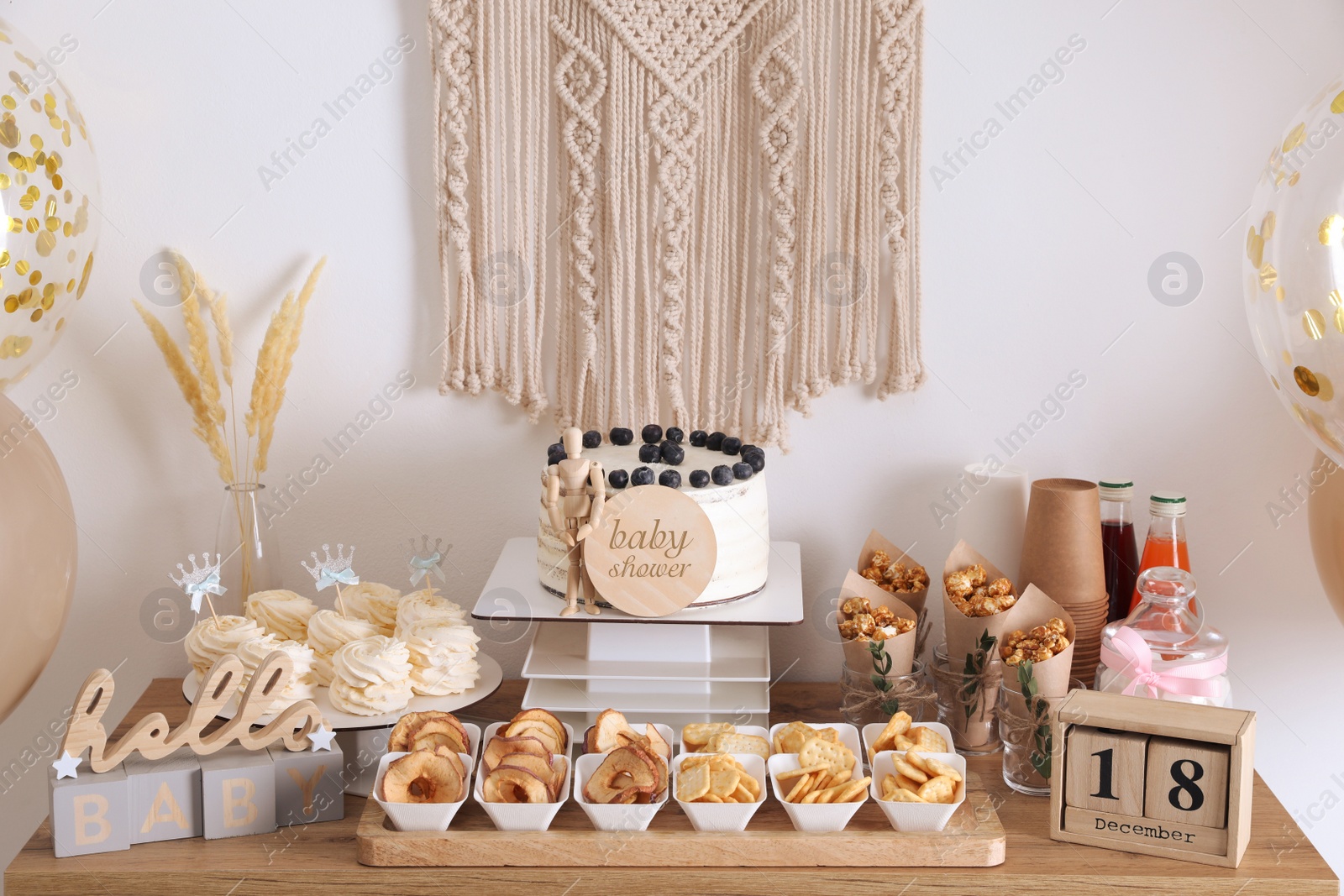 Photo of Baby shower party. Different delicious treats on wooden table and decor near light wall