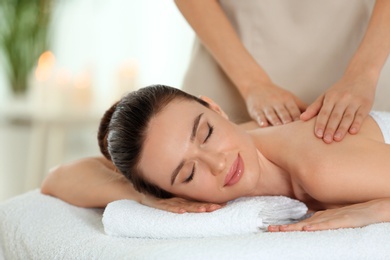 Photo of Beautiful young woman enjoying massage in spa salon