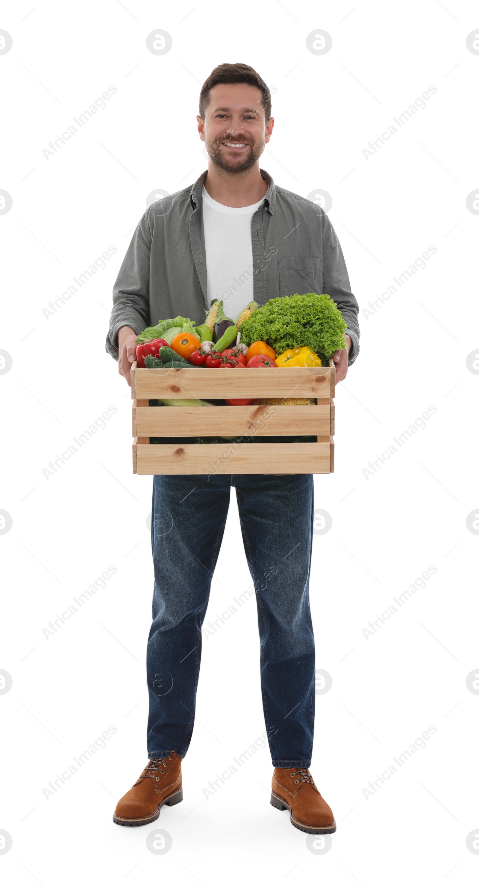 Photo of Harvesting season. Happy farmer holding wooden crate with vegetables on white background