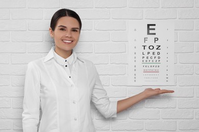 Ophthalmologist showing vision test chart on white brick wall