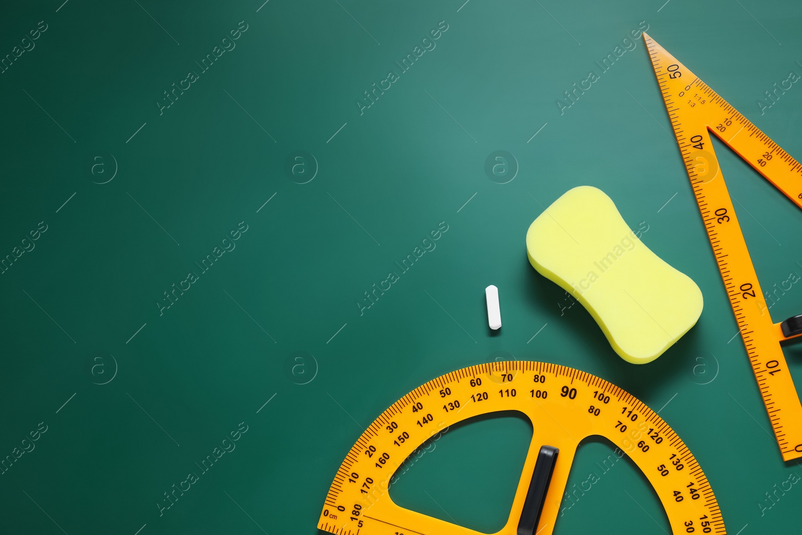 Photo of Protractor, triangle, sponge and chalk on green chalkboard, flat lay. Space for text