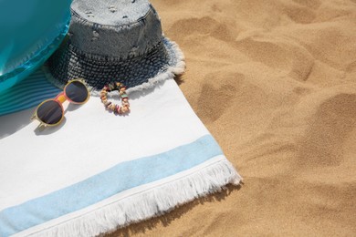Denim hat and beach accessories on sand, above view. Space for text