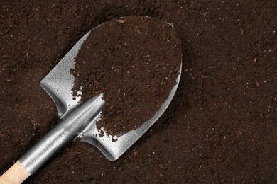 Photo of Metal shovel on fertile soil, top view and space for text. Gardening tool