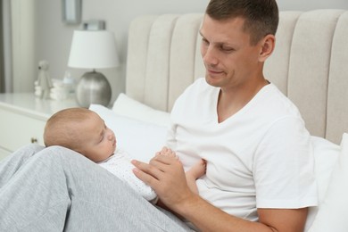 Photo of Happy father with his cute sleeping baby on bed at home