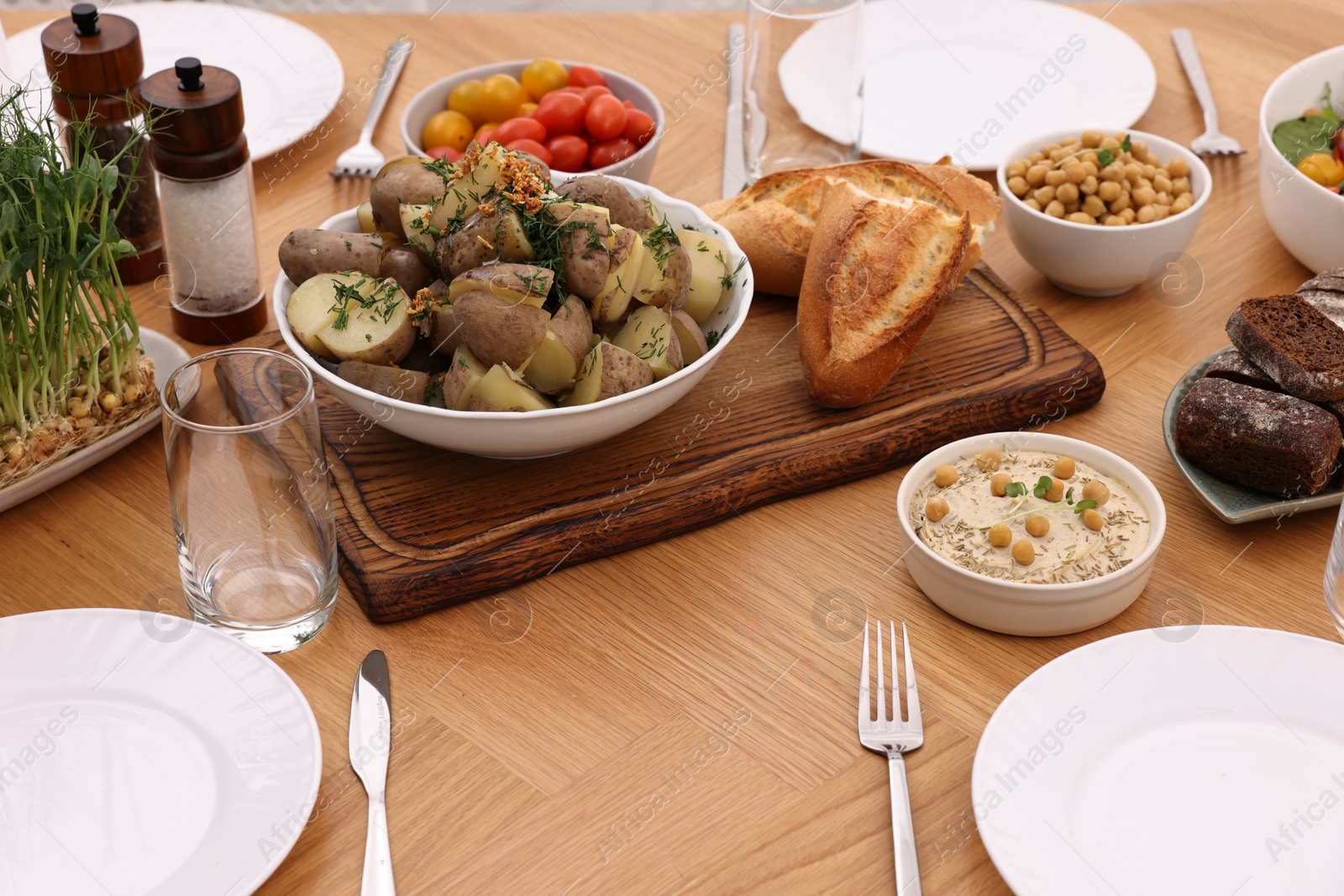 Photo of Healthy vegetarian food, glasses, cutlery and plates on wooden table