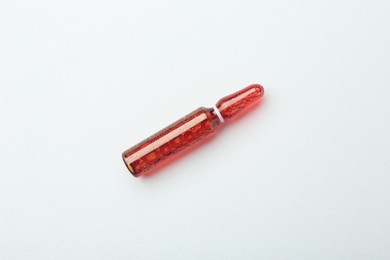 Photo of Glass ampoule with liquid on white background, top view