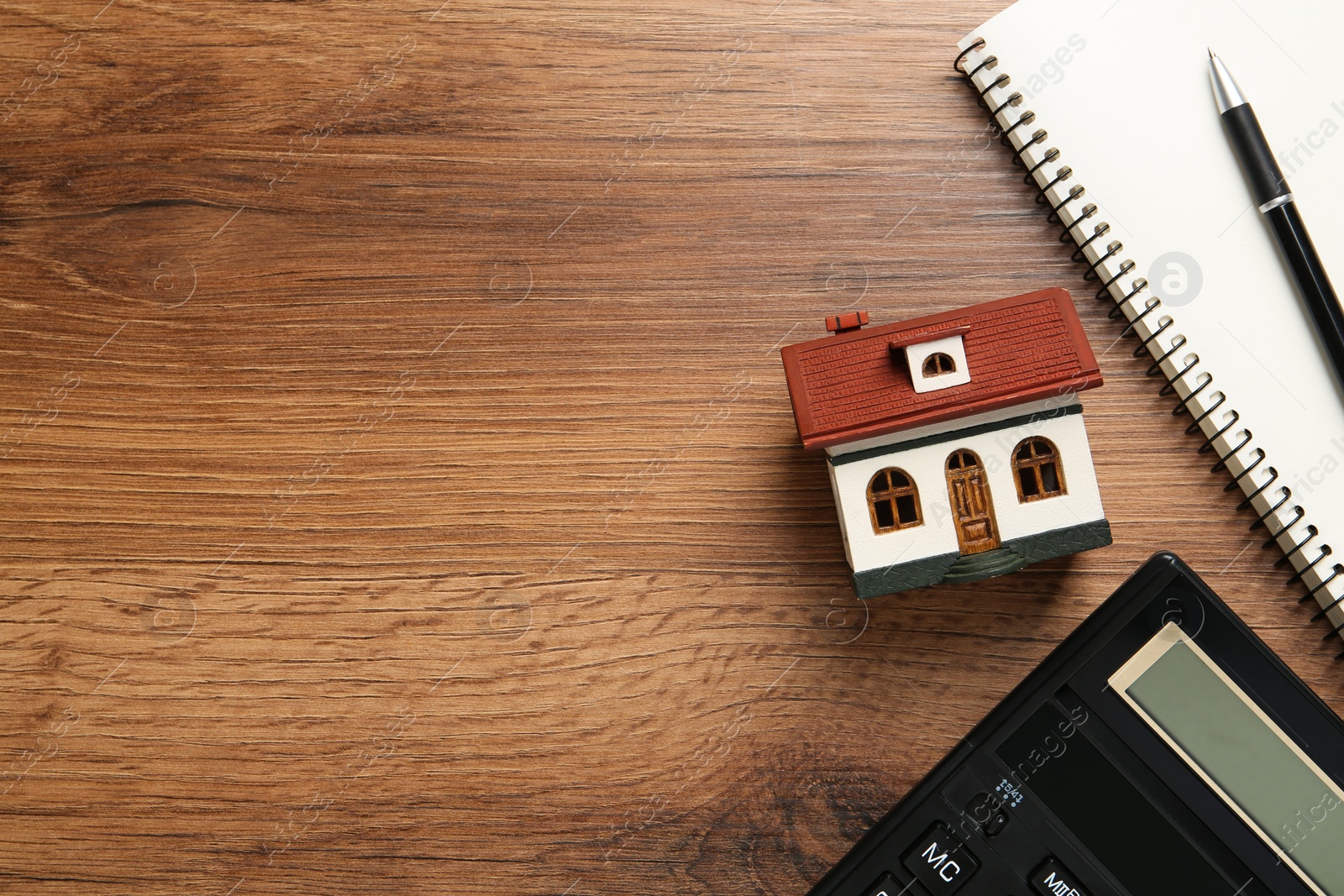 Photo of Mortgage concept. House model, notebook and calculator on wooden table, flat lay with space for text