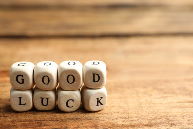 Photo of Cubes with phrase GOOD LUCK on wooden table, closeup. Space for text