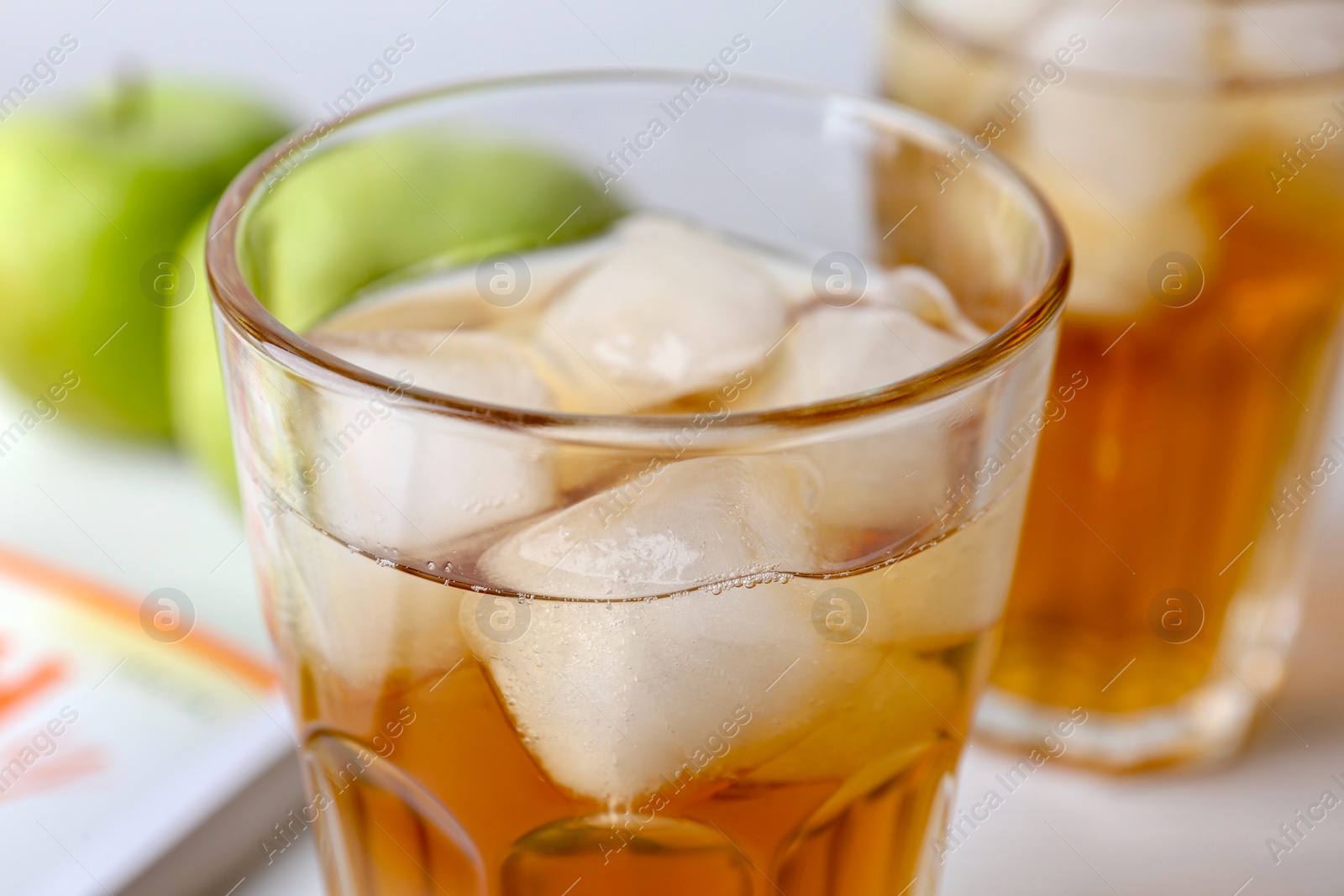 Photo of Glass of fresh apple juice with ice on table, closeup