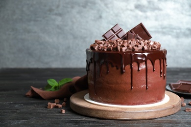 Photo of Freshly made delicious chocolate cake on black wooden table against grey background. Space for text