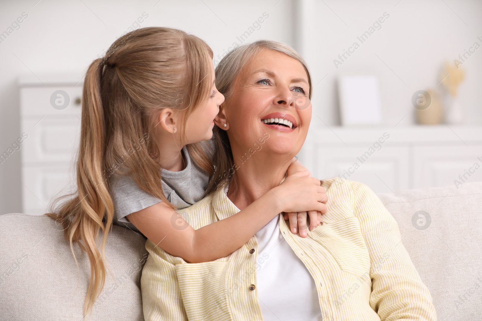 Photo of Happy grandmother hugging her granddaughter at home