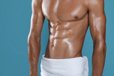 Photo of Shirtless man with slim body and towel wrapped around his hips on light blue background, closeup