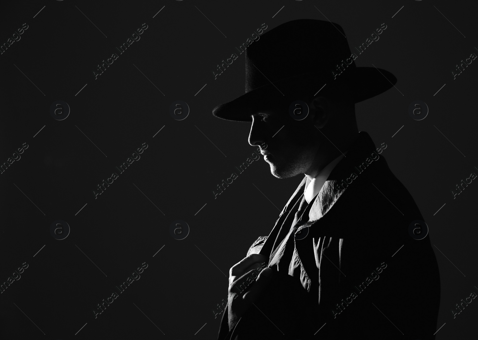 Photo of Old fashioned detective in hat on dark background, black and white effect. Space for text