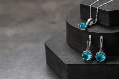 Photo of Beautiful jewelry with light blue gemstones on black podiums, space for text