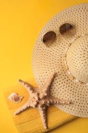Photo of Beach accessories, shell and starfish on orange background, flat lay