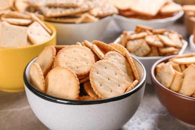 Delicious crackers in bowls on table, closeup