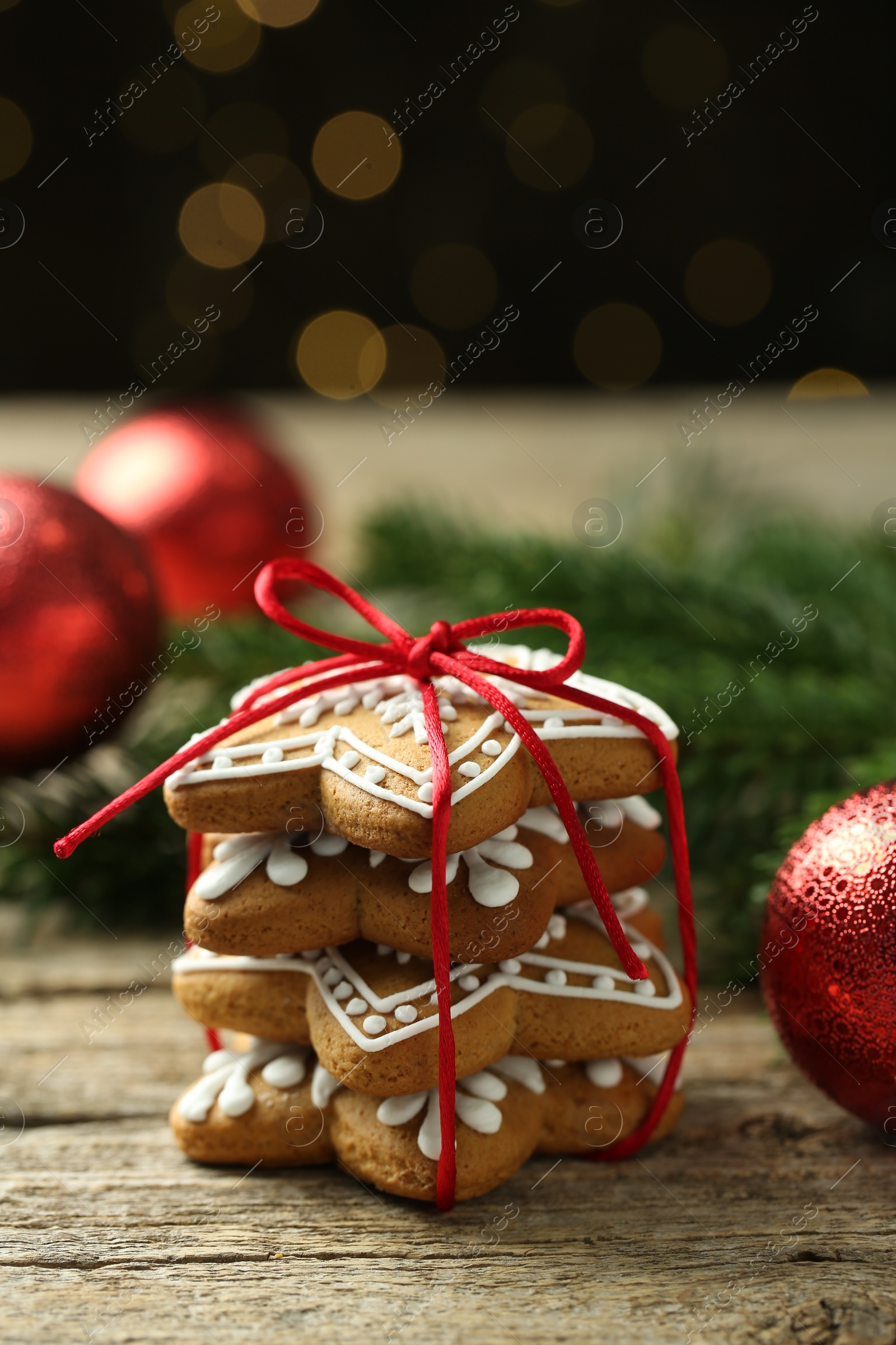 Photo of Tasty Christmas cookies with icing on wooden table against blurred lights