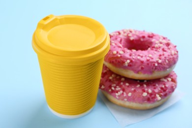 Photo of Two delicious donuts with sprinkles and hot drink on light blue background