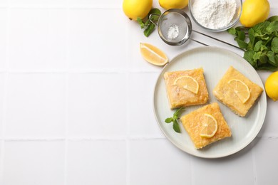 Photo of Tasty lemon bars with mint on white tiled table, flat lay. Space for text