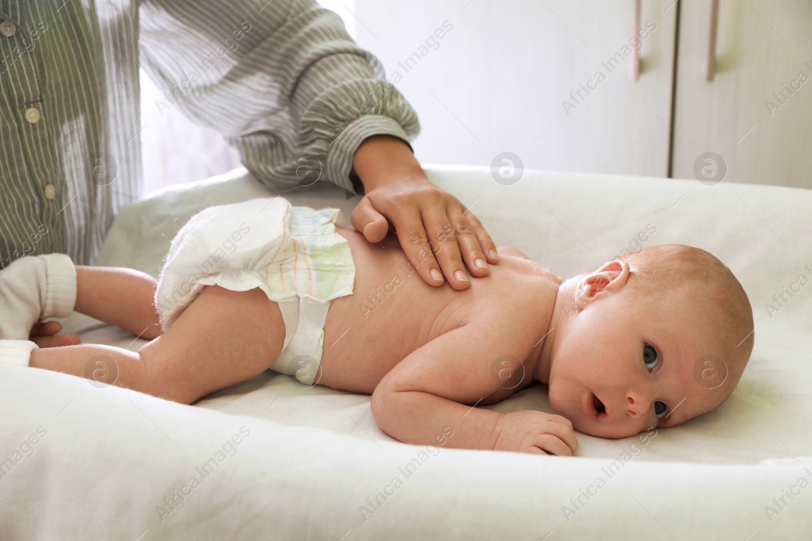 Photo of Mother massaging her little baby on changing table indoors, closeup