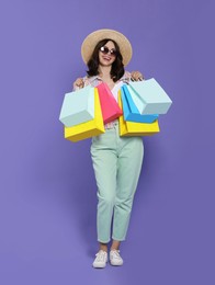 Photo of Beautiful young woman with paper shopping bags on purple background