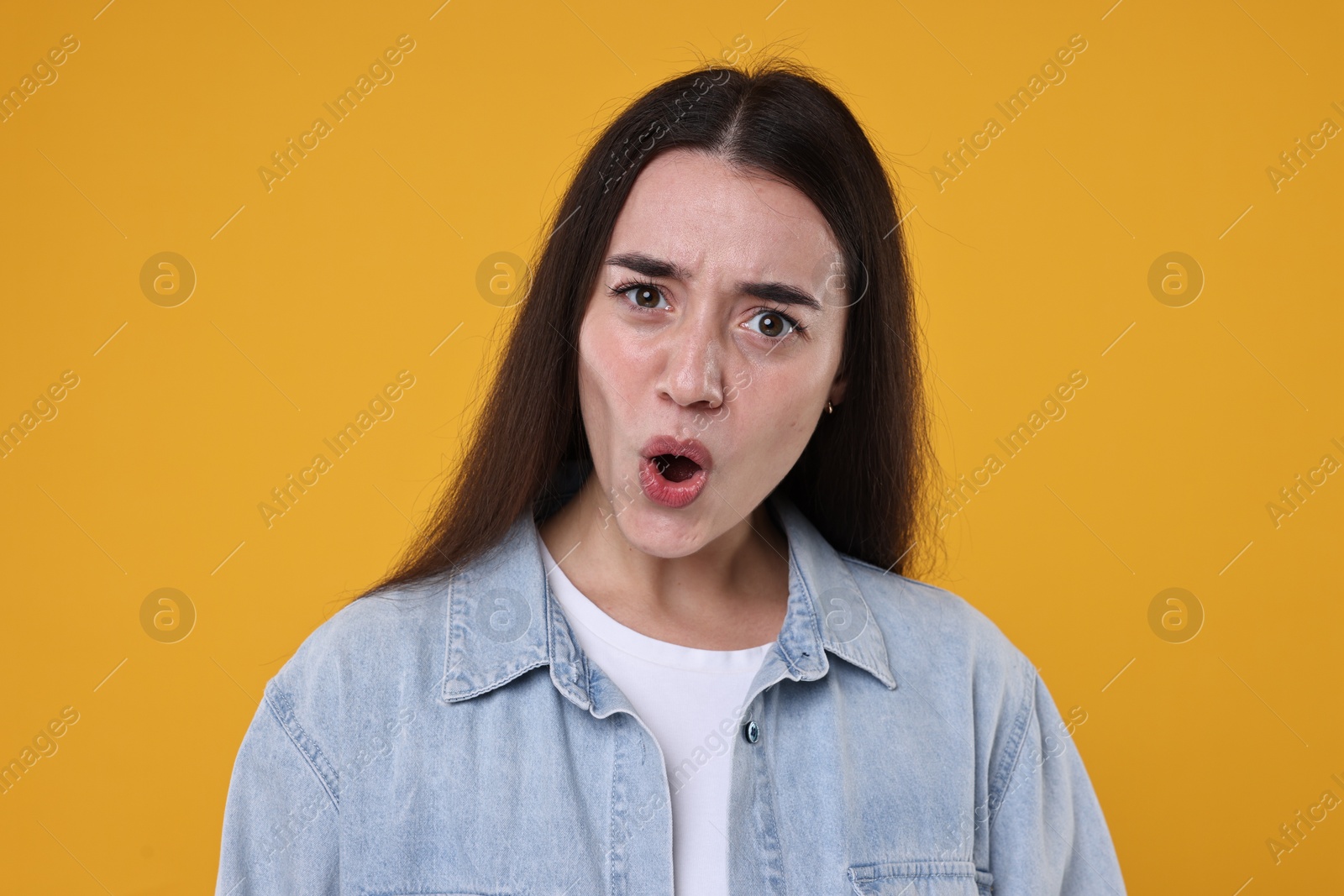 Photo of Portrait of surprised woman on orange background