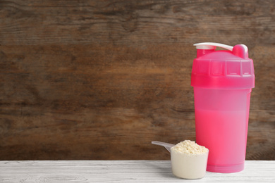 Photo of Protein shake and powder on white wooden table, space for text