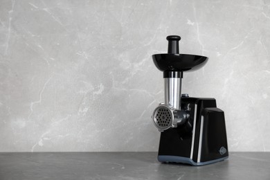 Photo of Modern electric meat grinder on grey table. Space for text