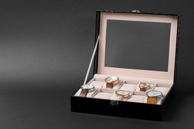 Photo of Jewelry box with many different wristwatches on dark gray background, space for text