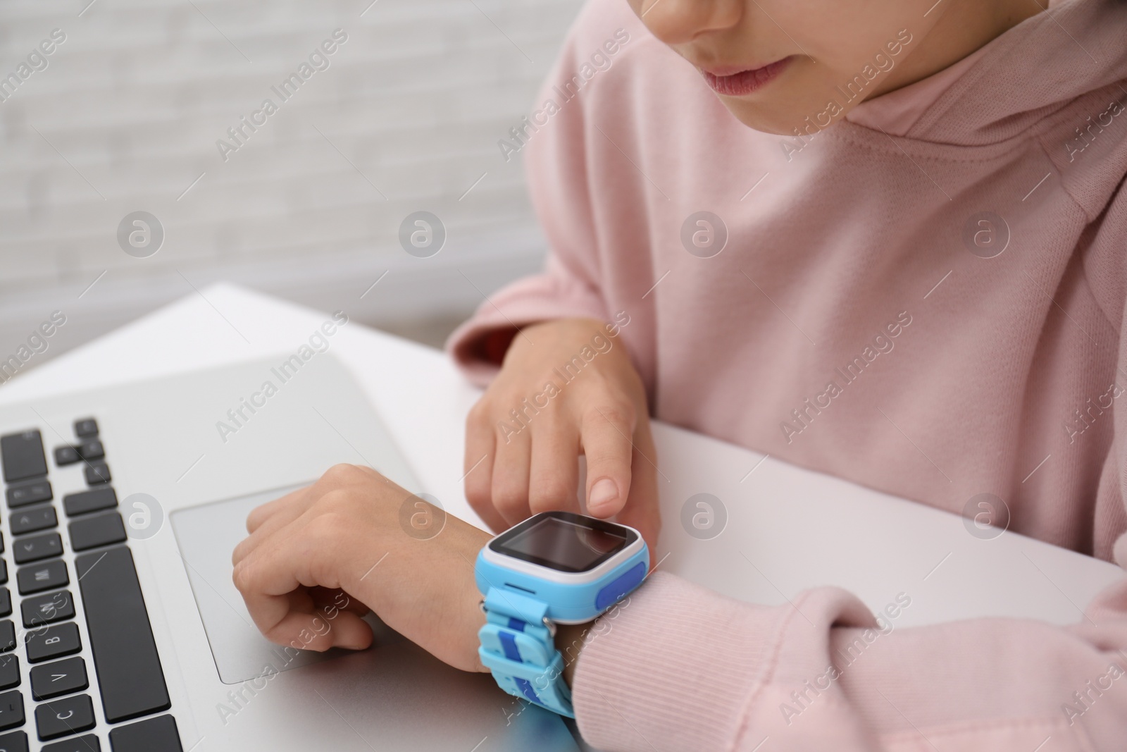 Photo of Girl with stylish smart watch at table, closeup