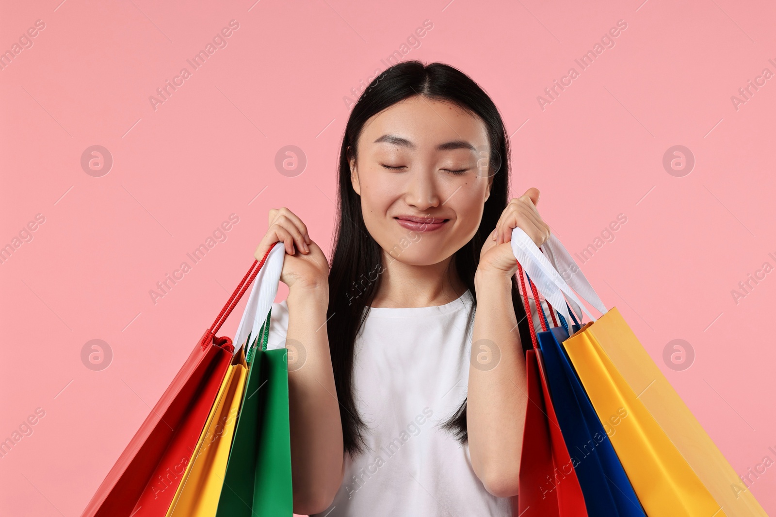 Photo of Happy woman with shopping bags on pink background