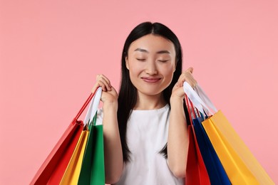 Photo of Happy woman with shopping bags on pink background