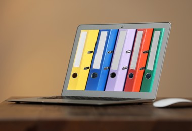 Image of Store and organize information. Modern laptop with hardcover office folders on screen